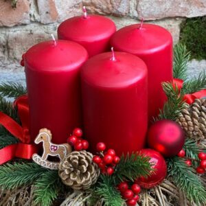 Adventní věnec na proutěném základu se čtyřmi červenými svíčkami a houpacím koníkem