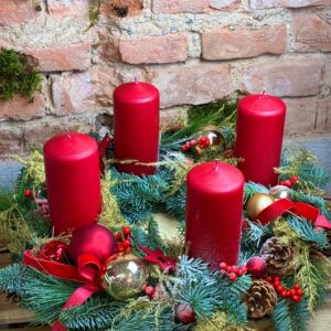 Adventní věnec se čtyřmi červenými svíčkami a červenými stuhami